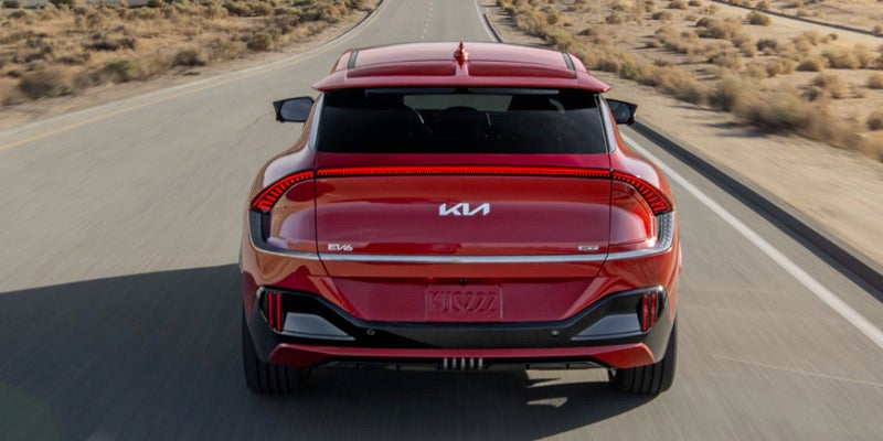 Rearview of a red 2023 Kia EV6 driving down a paved road